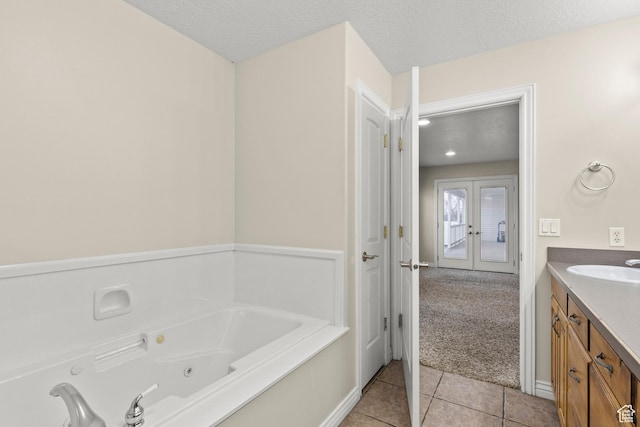 full bathroom featuring a textured ceiling, french doors, vanity, tile patterned flooring, and a whirlpool tub