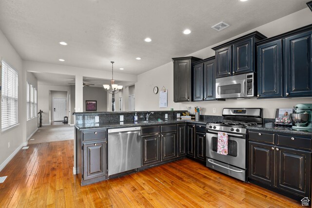 11709 S Grandville Ave, South Jordan, UT 84009 - kitchen with stainless steel appliances, a peninsula, a chandelier, light wood-style flooring, and recessed lighting