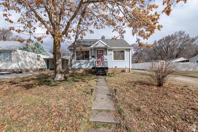 bungalow-style home featuring a chimney and fence