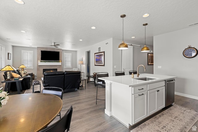 415 W 1410 N Unit 81, Tooele, UT 84074 - kitchen featuring wood finished floors, a ceiling fan, a center island with sink, a sink, and a large fireplace