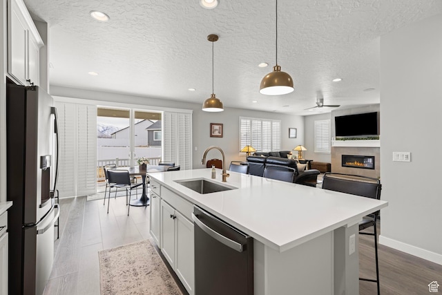 415 W 1410 N Unit 81, Tooele, UT 84074 - kitchen with light countertops, appliances with stainless steel finishes, a glass covered fireplace, a ceiling fan, and a sink