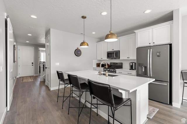 415 W 1410 N Unit 81, Tooele, UT 84074 - kitchen featuring a center island with sink, a kitchen breakfast bar, wood finished floors, stainless steel appliances, and decorative backsplash
