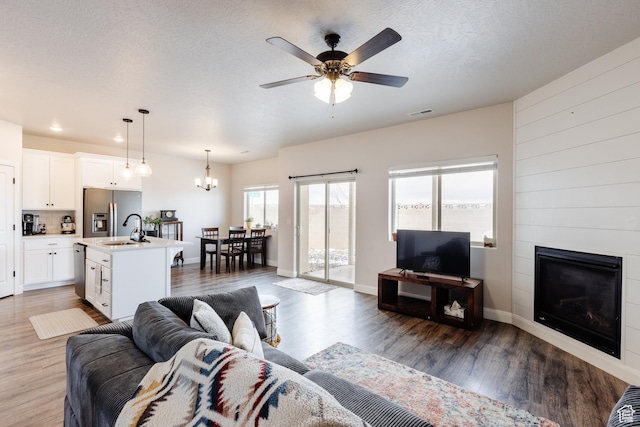 3084 W 1750 N Unit 1, Cedar City, UT 84721 - living area with ceiling fan with notable chandelier, a textured ceiling, wood finished floors, and a large fireplace