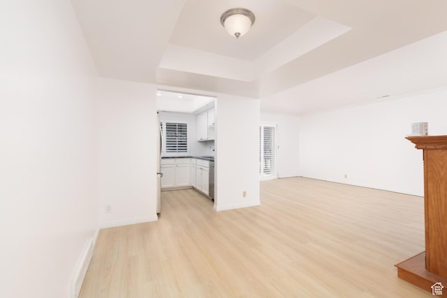 1525 E Waterbury Dr Unit D, Salt Lake City, UT 84121 - unfurnished living room featuring light wood-type flooring, a raised ceiling, and baseboards