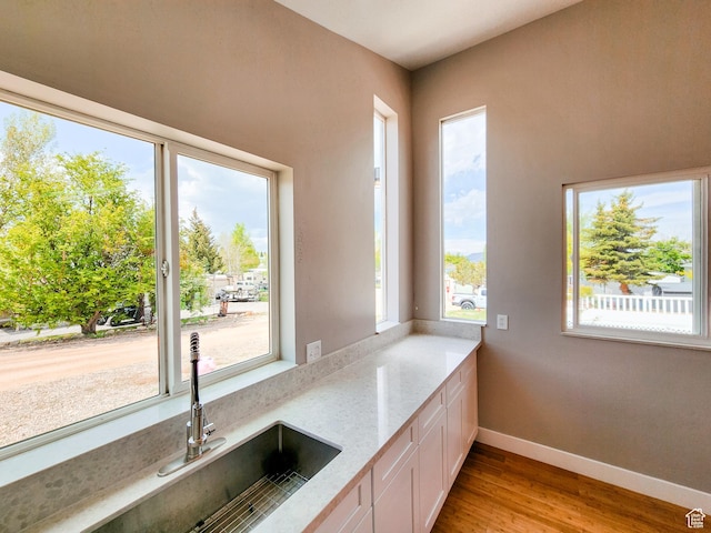 3030 S Edgemont Dr Unit 159, Garden City, UT 84028 - kitchen with light stone counters, a sink, white cabinetry, light wood finished floors, and baseboards