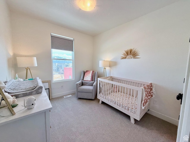 carpeted bedroom with visible vents, baseboards, and a nursery area