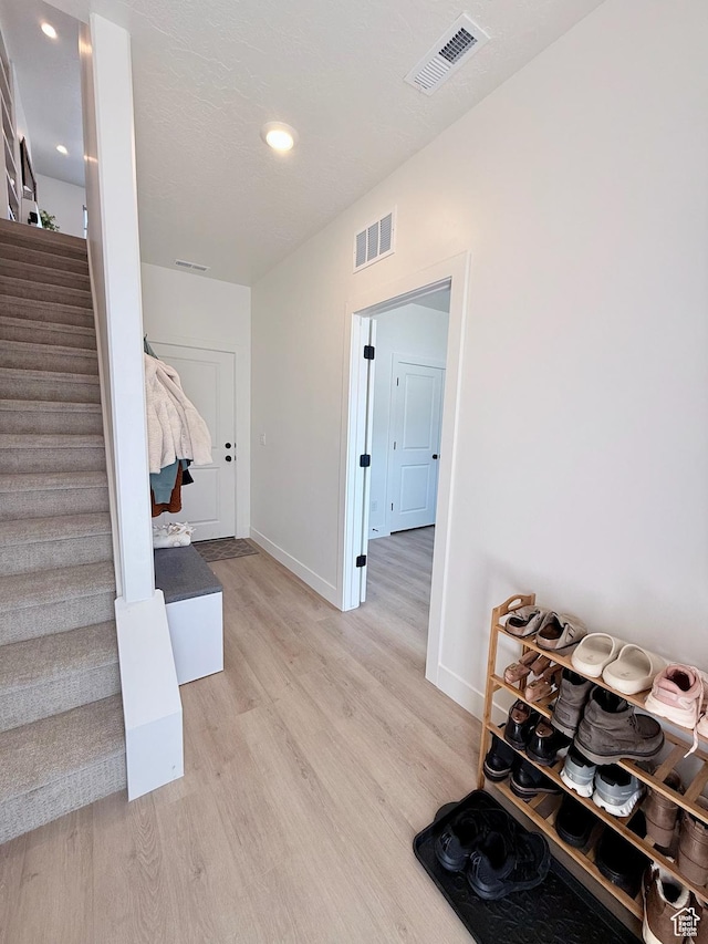 interior space with visible vents, baseboards, light wood-style flooring, and stairway