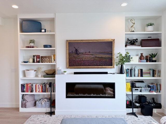 living area featuring recessed lighting, built in shelves, baseboards, and wood finished floors