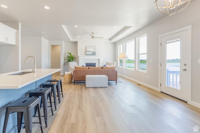 3077 N 2875 W Unit 5, Plain City, UT 84404 - living room featuring recessed lighting, ceiling fan with notable chandelier, a raised ceiling, light wood-style floors, and a fireplace