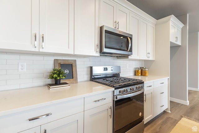 3077 N 2875 W Unit 5, Plain City, UT 84404 - kitchen featuring light wood finished floors, white cabinetry, baseboards, appliances with stainless steel finishes, and tasteful backsplash