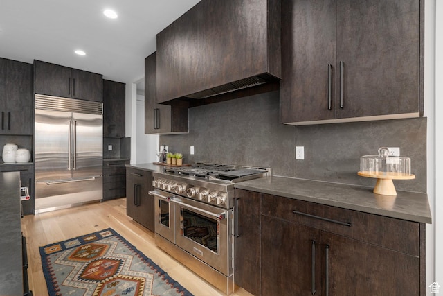 915 Farrell Farm Cir, Midway, UT 84049 - kitchen with premium range hood, premium appliances, light wood finished floors, decorative backsplash, and dark brown cabinets