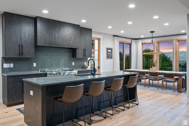 915 Farrell Farm Cir, Midway, UT 84049 - kitchen featuring an island with sink, a sink, stove, light wood-style floors, and a kitchen breakfast bar