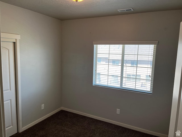 223 E Jordan Ridge Blvd Unit 110, Saratoga Springs, UT 84045 - empty room with visible vents, dark carpet, a textured ceiling, and baseboards