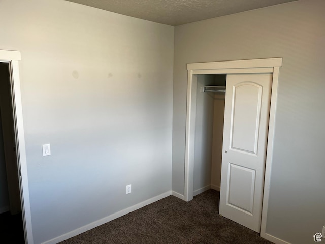 223 E Jordan Ridge Blvd Unit 110, Saratoga Springs, UT 84045 - unfurnished bedroom featuring a closet, baseboards, dark carpet, and a textured ceiling