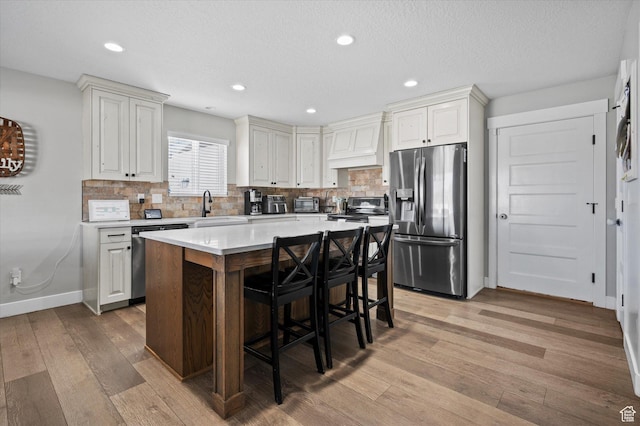 1490 N 4925 W, Plain City, UT 84404 - kitchen with light wood-style flooring, custom range hood, a sink, stainless steel appliances, and a breakfast bar area