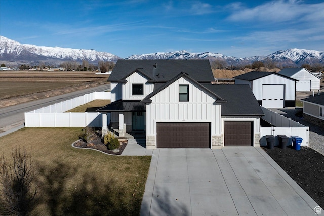 1490 N 4925 W, Plain City, UT 84404 - modern farmhouse style home with a front lawn, stone siding, fence, a mountain view, and board and batten siding