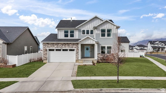 craftsman-style house featuring board and batten siding, fence, concrete driveway, a front yard, and stone siding