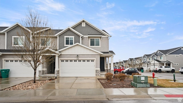 view of front of property with stone siding, a residential view, board and batten siding, concrete driveway, and a garage
