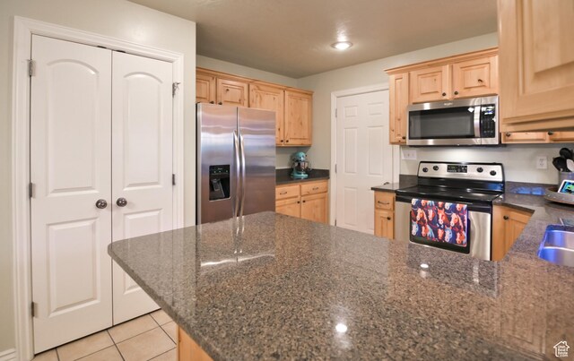 3131 E River Bottoms Rd S, Spanish Fork, UT 84660 - kitchen with dark stone countertops, light tile patterned flooring, a peninsula, light brown cabinets, and appliances with stainless steel finishes