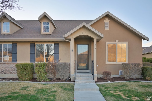 view of front of house featuring stucco siding, roof with shingles, and a front lawn