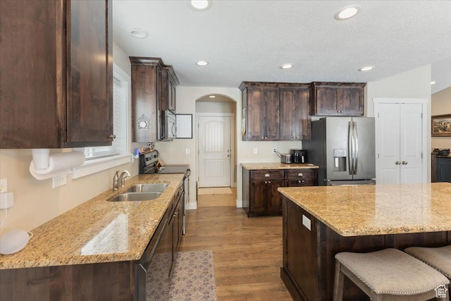 7114 N 2275 W, Honeyville, UT 84314 - kitchen featuring dark brown cabinetry, arched walkways, a sink, and appliances with stainless steel finishes