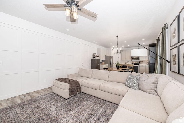 198 W Box Creek Dr, Stansbury Park, UT 84074 - living room with recessed lighting, ceiling fan with notable chandelier, a decorative wall, and light wood-style flooring