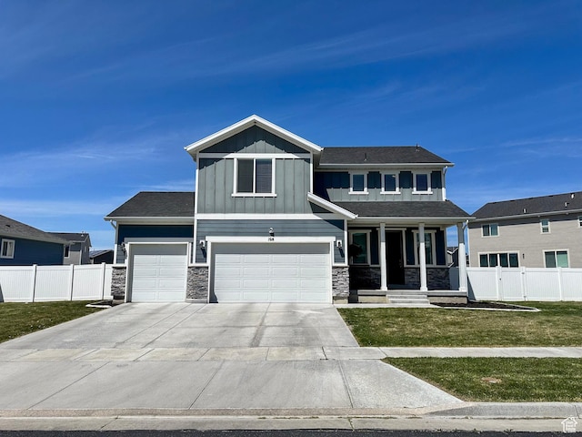 craftsman inspired home featuring board and batten siding, stone siding, a front lawn, and fence