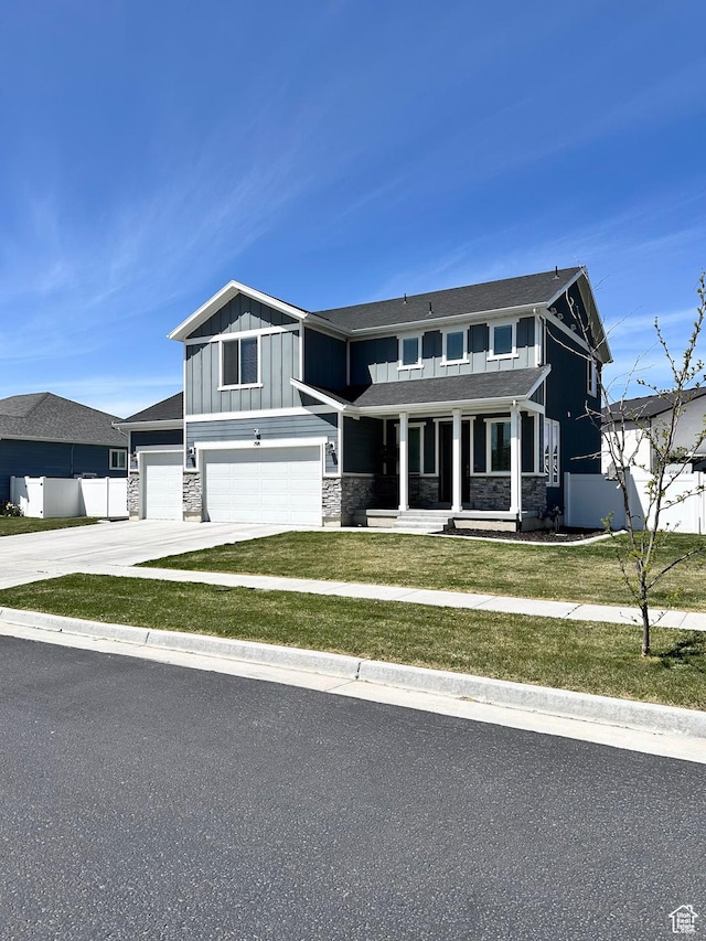198 W Box Creek Dr, Stansbury Park, UT 84074 - view of front facade featuring concrete driveway, an attached garage, board and batten siding, stone siding, and a porch