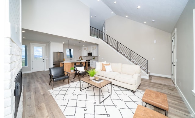 2678 S Eagle Dr Unit 12, Garden City, UT 84028 - living room featuring light wood-style flooring, baseboards, a stone fireplace, and high vaulted ceiling