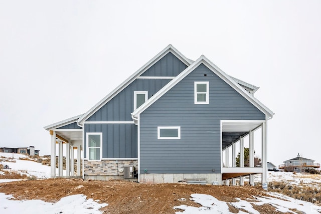 2678 S Eagle Dr Unit 12, Garden City, UT 84028 - view of snow covered exterior featuring central air condition unit, board and batten siding, and stone siding