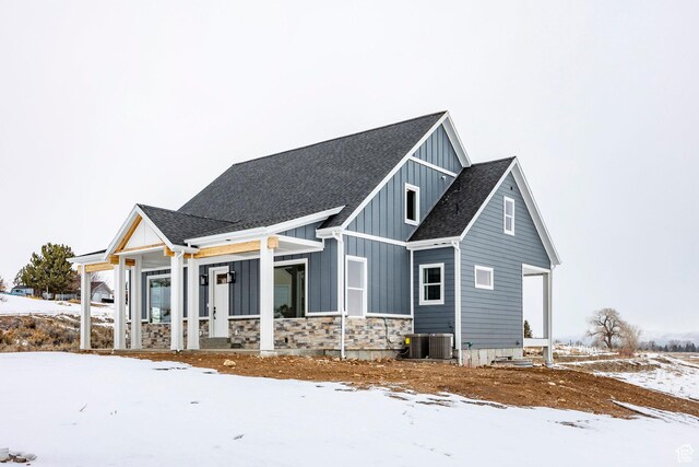 2678 S Eagle Dr Unit 12, Garden City, UT 84028 - view of snow covered exterior featuring a shingled roof, board and batten siding, a porch, and stone siding