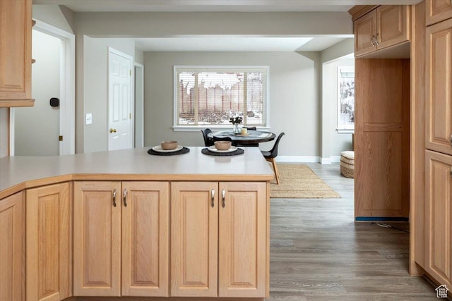 kitchen with light brown cabinets, light countertops, baseboards, and wood finished floors