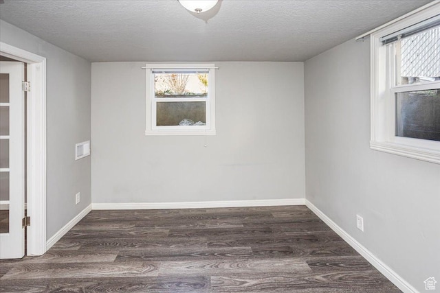 spare room with baseboards, a textured ceiling, and wood finished floors