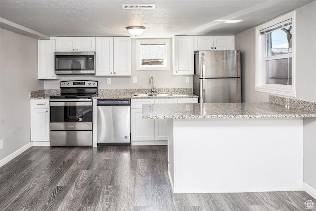 kitchen featuring white cabinets, visible vents, appliances with stainless steel finishes, and a sink
