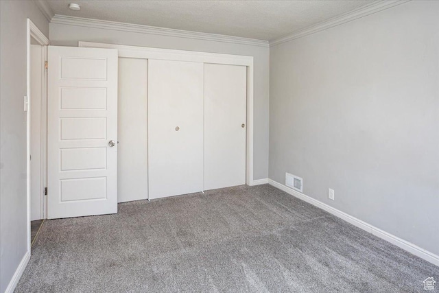 unfurnished bedroom featuring visible vents, crown molding, baseboards, carpet, and a closet