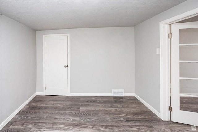 spare room with visible vents, a textured ceiling, baseboards, and wood finished floors