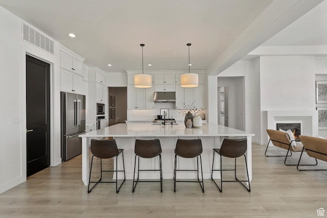 4784 W Juniper Bend Cir, Herriman, UT 84096 - kitchen with light wood-type flooring, visible vents, a breakfast bar, appliances with stainless steel finishes, and decorative backsplash