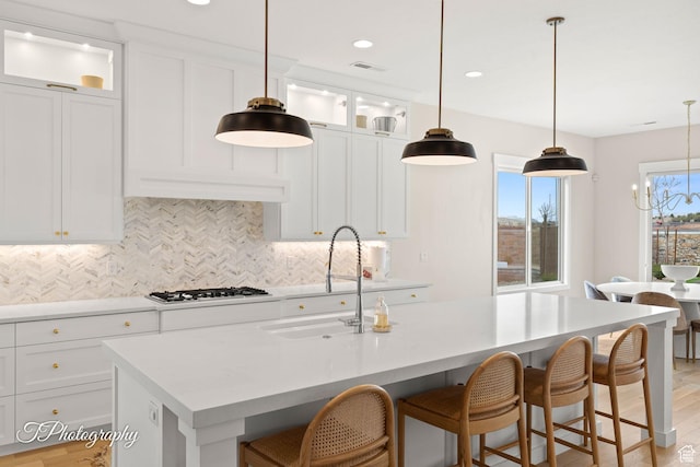 2092 S 3010 E, St George, UT 84790 - kitchen with a kitchen bar, a kitchen island with sink, a sink, gas cooktop, and tasteful backsplash