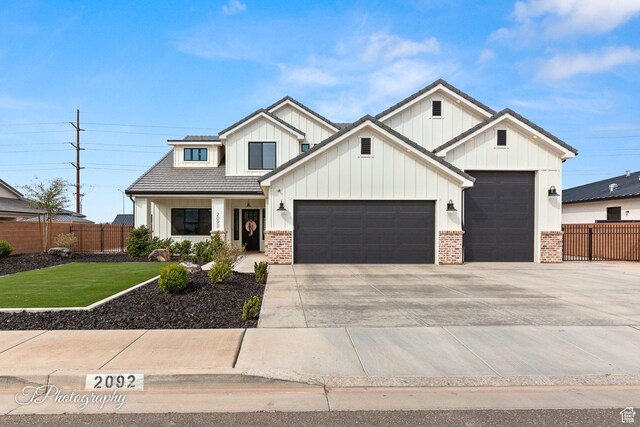 modern farmhouse featuring board and batten siding, a front lawn, fence, and a garage