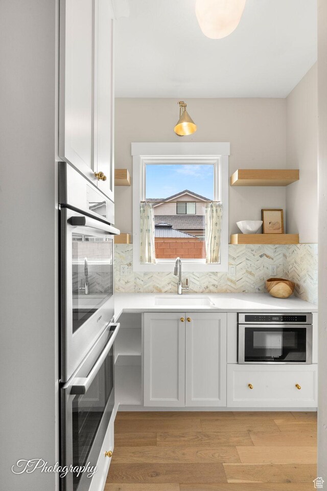 2092 S 3010 E, St George, UT 84790 - kitchen with a sink, tasteful backsplash, stainless steel double oven, light wood finished floors, and light countertops