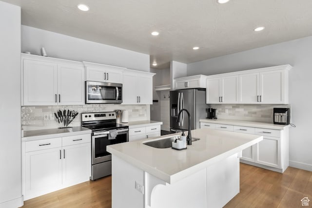 373 S 850 E, American Fork, UT 84003 - kitchen with an island with sink, a sink, white cabinets, light wood-style floors, and appliances with stainless steel finishes