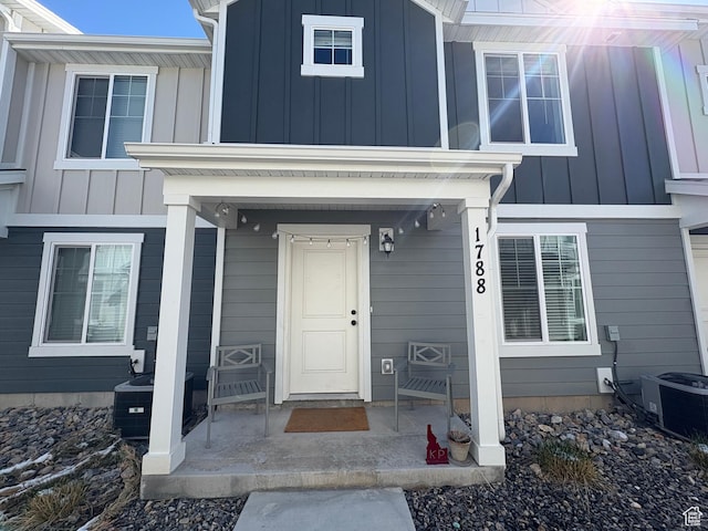 doorway to property with board and batten siding and central AC