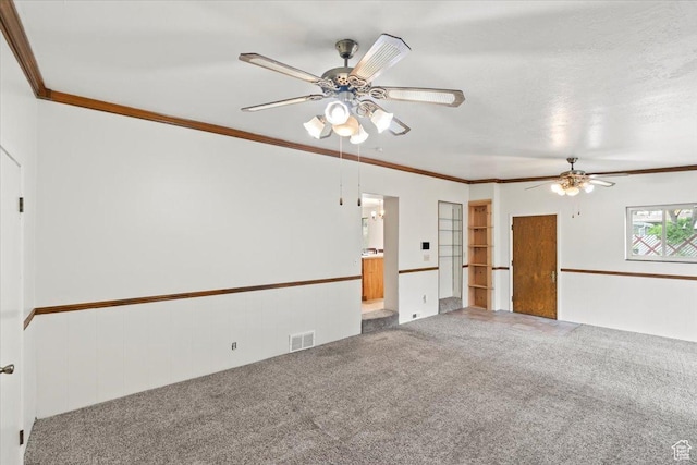 spare room featuring carpet flooring, wainscoting, visible vents, ceiling fan, and crown molding