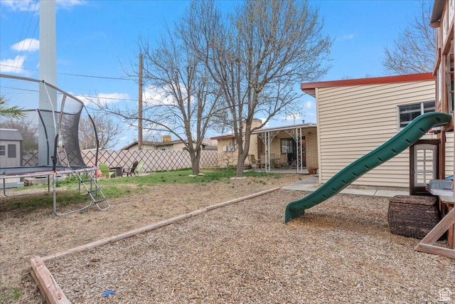 view of yard featuring a trampoline and fence