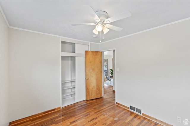 unfurnished bedroom featuring a closet, wood finished floors, visible vents, crown molding, and a ceiling fan