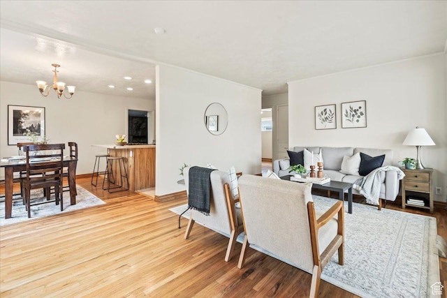 living area featuring crown molding, a notable chandelier, baseboards, and wood finished floors