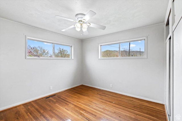 unfurnished bedroom featuring a closet, light wood-style flooring, baseboards, ornamental molding, and visible vents