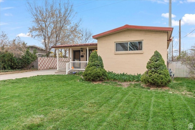 view of front of property with concrete driveway, covered porch, a front lawn, and fence