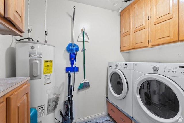 clothes washing area featuring washing machine and clothes dryer, water heater, and cabinet space