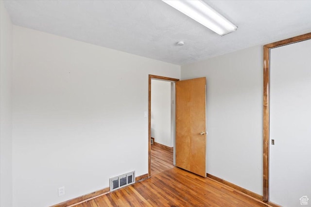 spare room featuring baseboards, light wood-type flooring, and visible vents